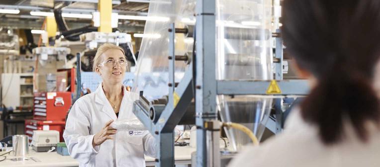 UQ researchers feed a large sheet of plastic through a machine in a research lab
